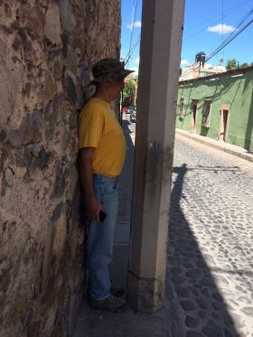 Man standing next to a pole on the sidewalk in Mexico